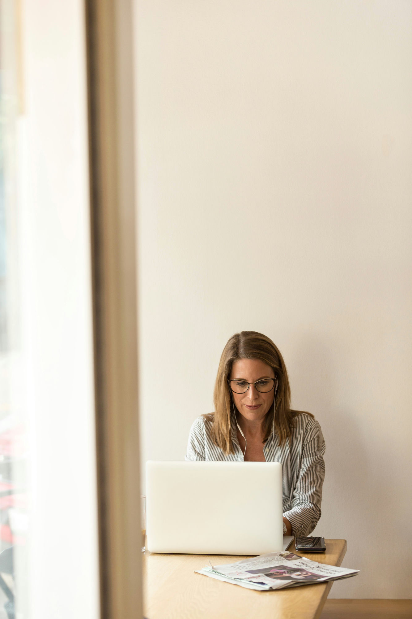 A professional working at a laptop by a window.